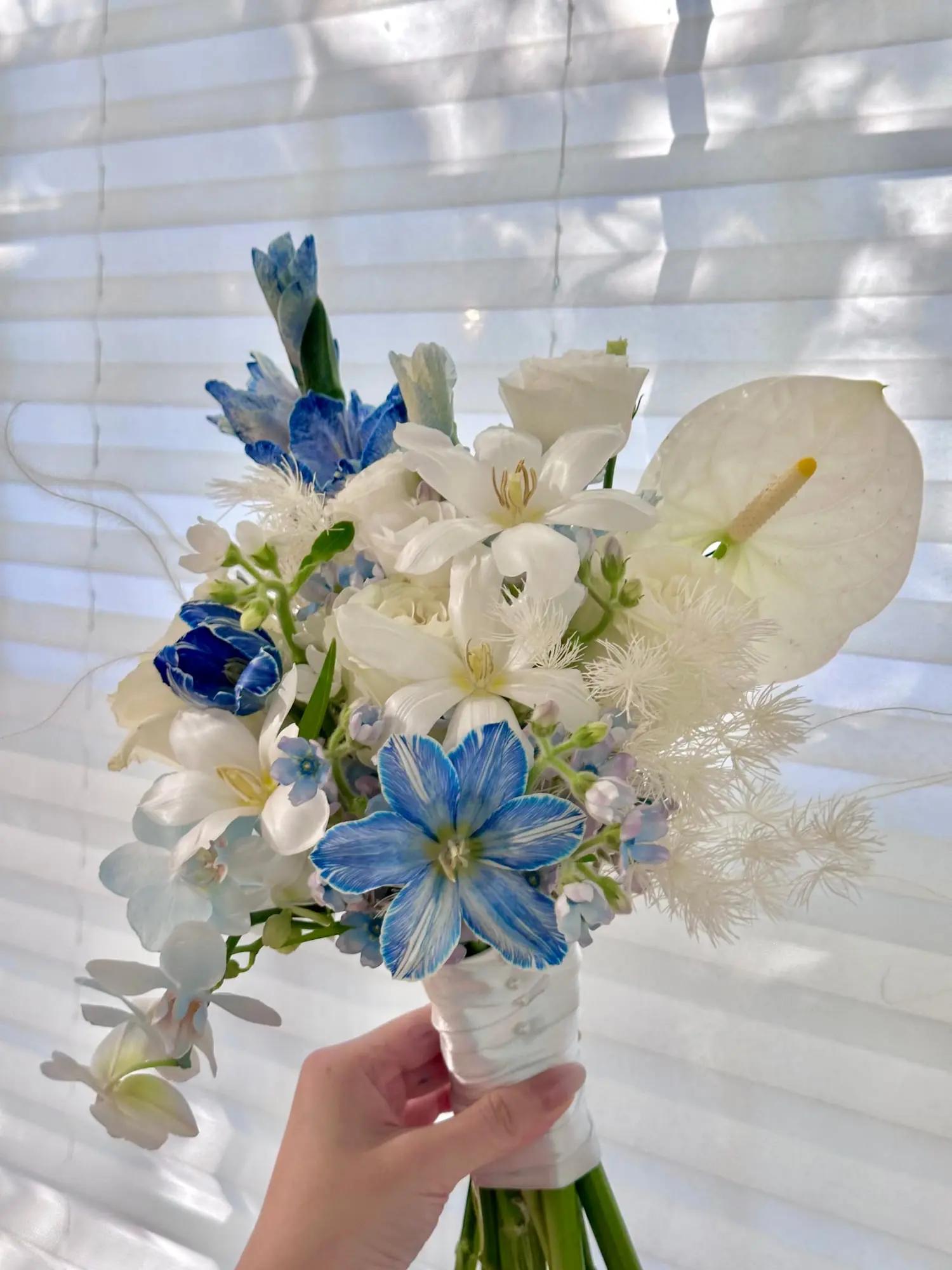 A bridal bouquet kissed by light and sky — with delicate orchids, starry blues, and snow-white blooms. For the ones who bloom in grace and clarity.