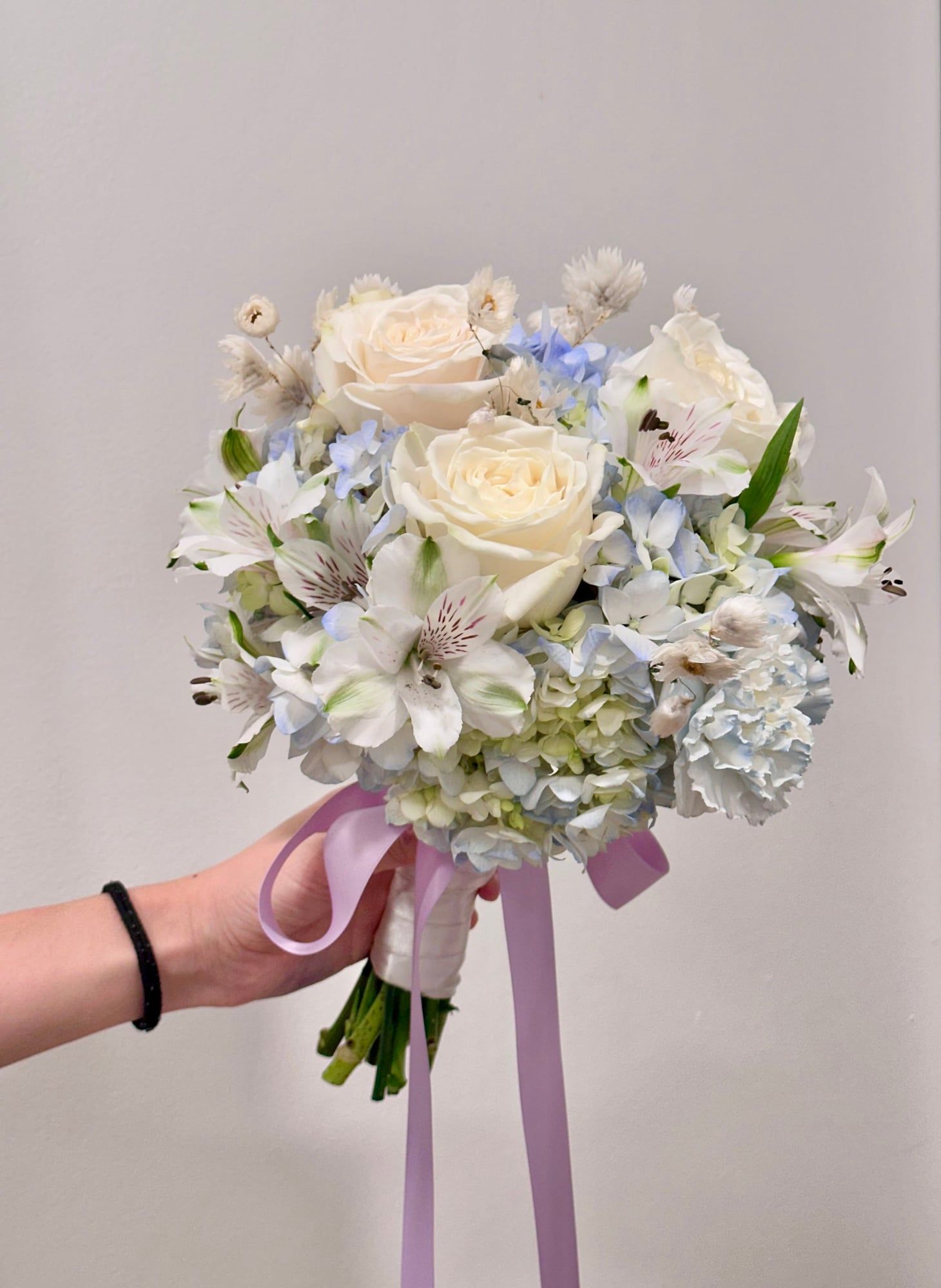 A bouquet in hues of ivory, sky blue, and lilac — gentle yet elegant, like a whisper of love. Perfect for your “I do” or a forever memory.