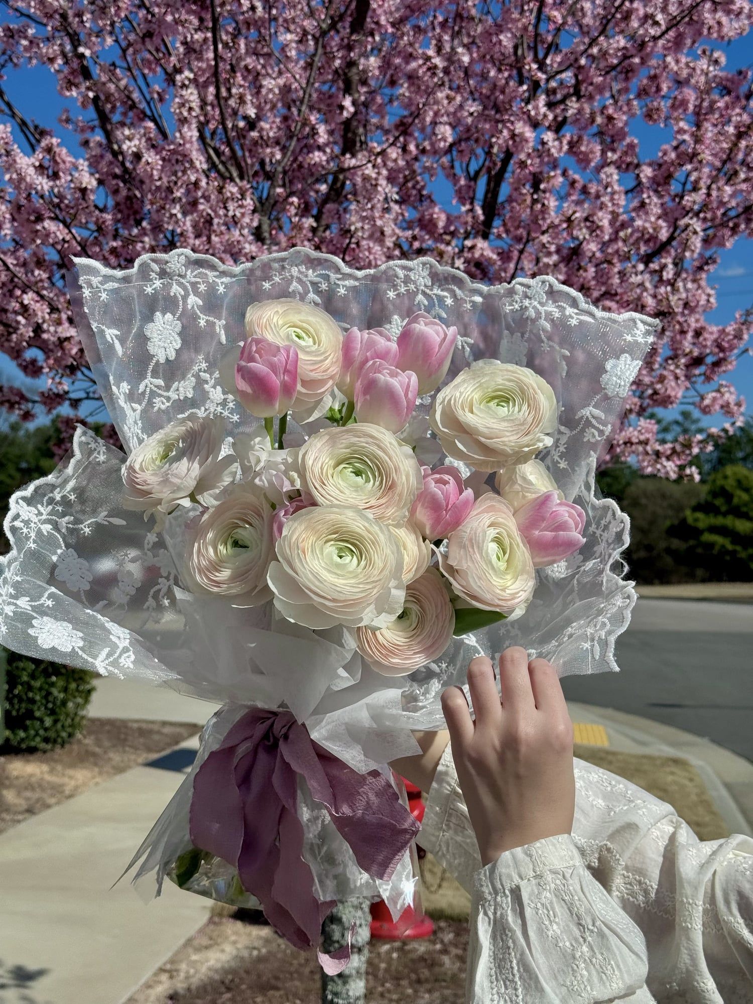 Soft as a breeze and delicate as a dream, this bouquet features layers of blush pink ranunculus, tulips, and Sweet Pea wrapped in lace and sheer fabric for a romantic, vintage feel
